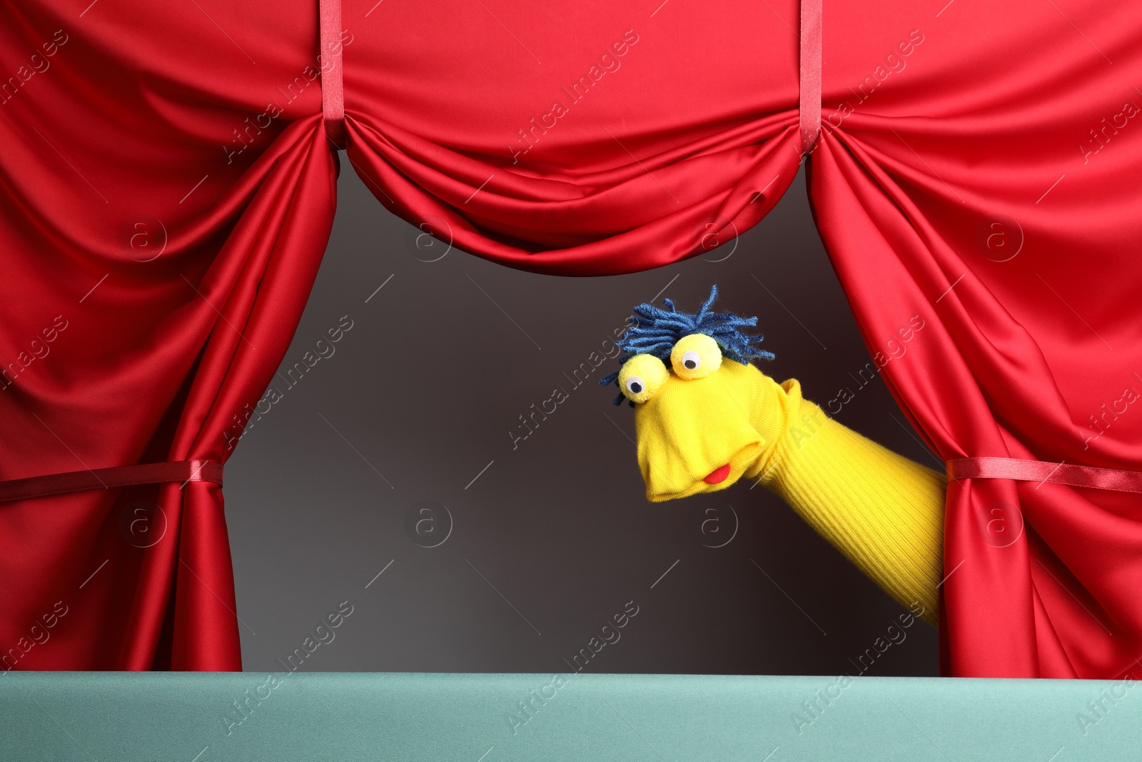 Photo of Creative puppet show on stage with red curtains