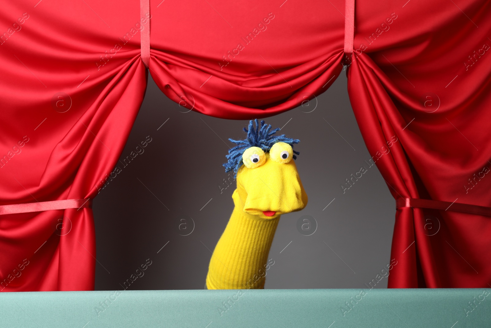Photo of Creative puppet show on stage with red curtains