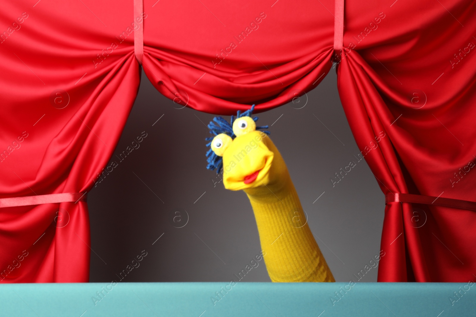 Photo of Creative puppet show on stage with red curtains