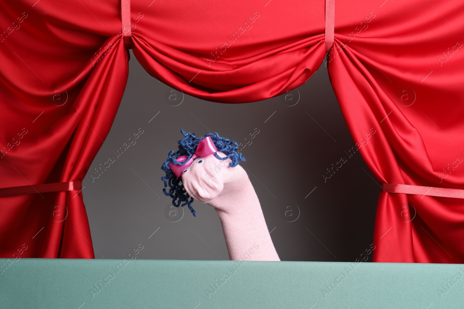 Photo of Creative puppet show on stage with red curtains