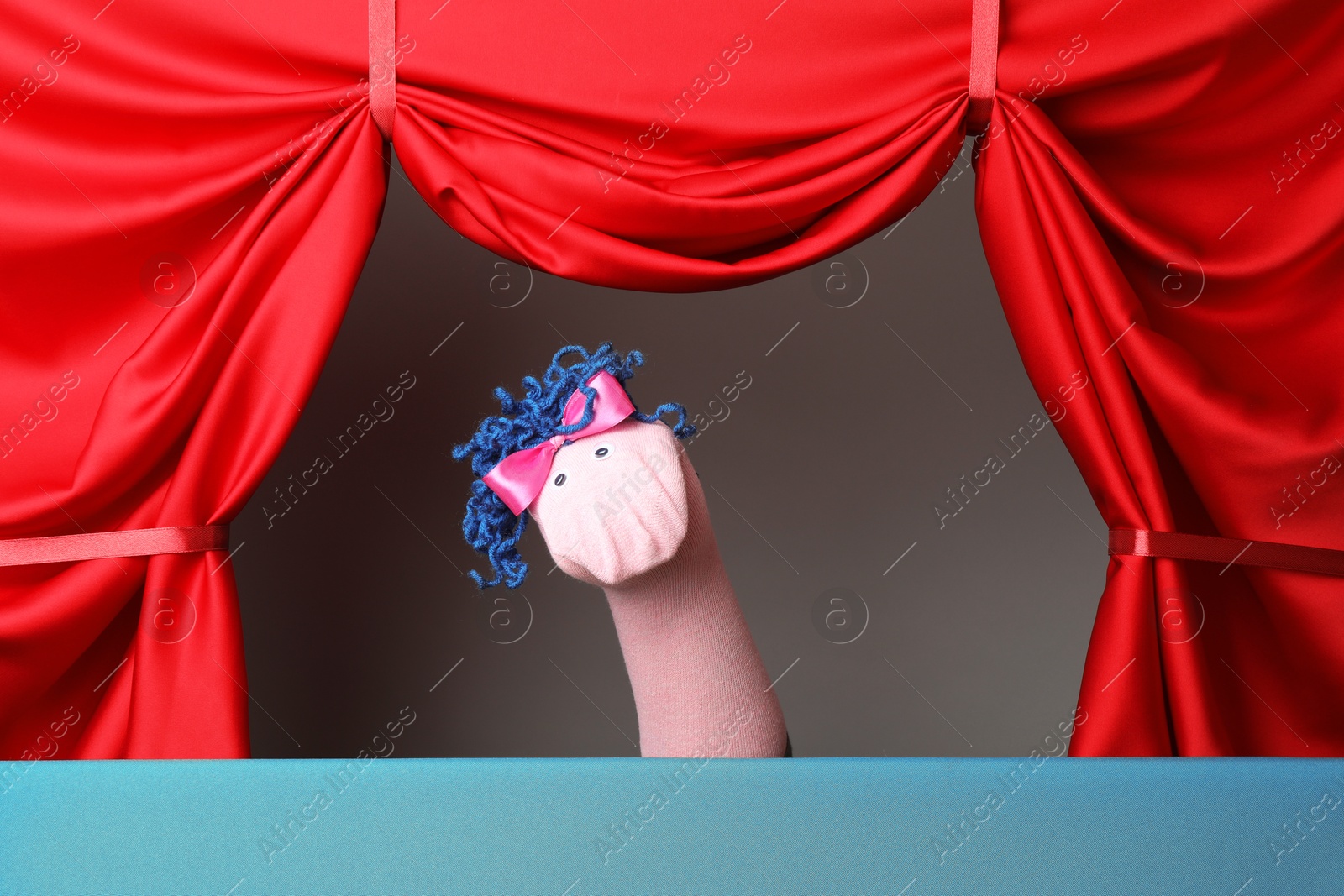 Photo of Creative puppet show on stage with red curtains