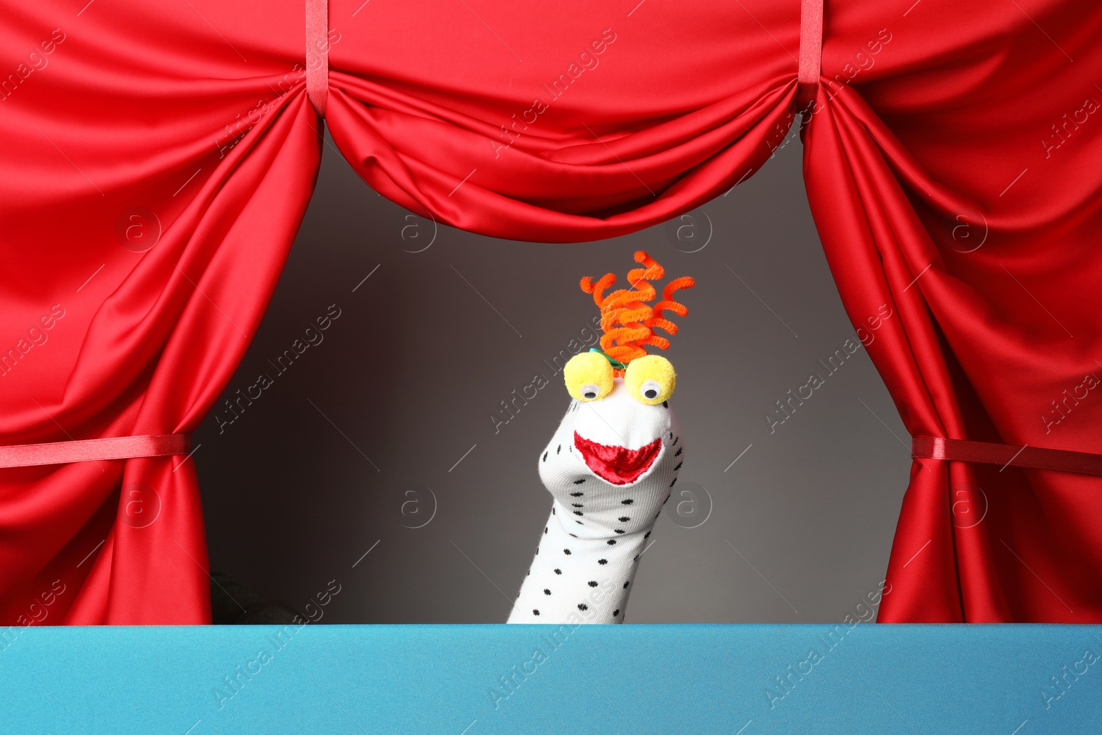 Photo of Creative puppet show on stage with red curtains
