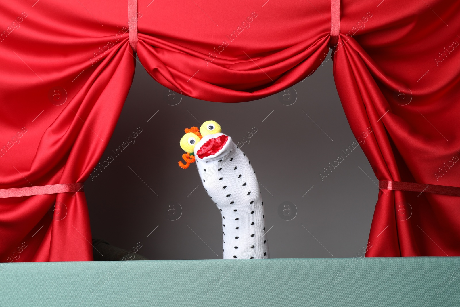 Photo of Creative puppet show on stage with red curtains
