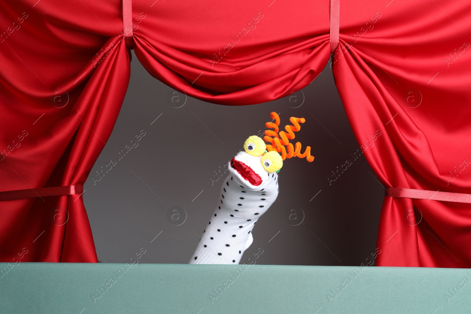 Photo of Creative puppet show on stage with red curtains