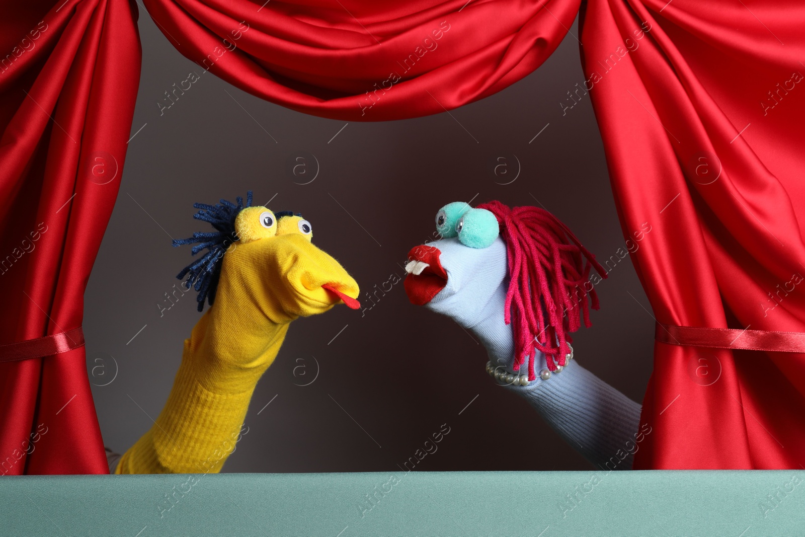 Photo of Creative puppet show on stage with red curtains