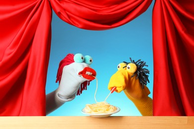 Photo of Creative puppet show on wooden stage with prop and red curtains