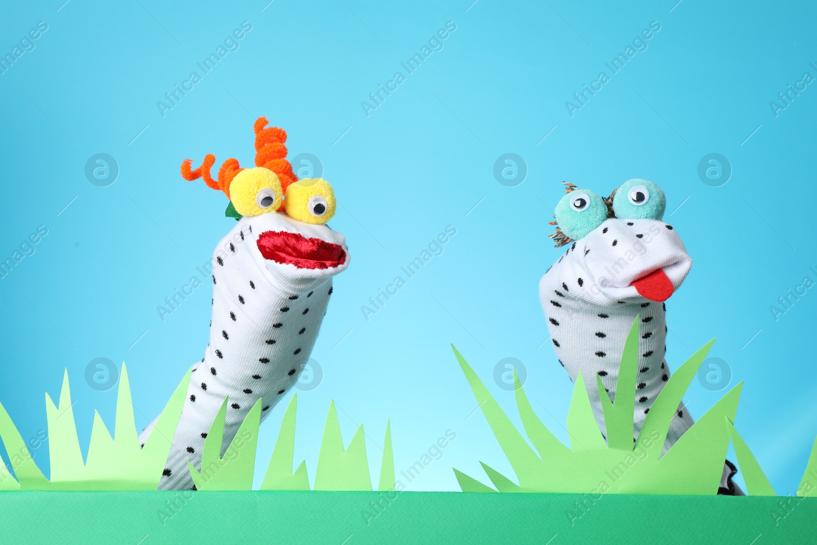 Creative puppet show on stage with decorations against light blue background Photo of Creative puppet show on stage with decorations against light blue background