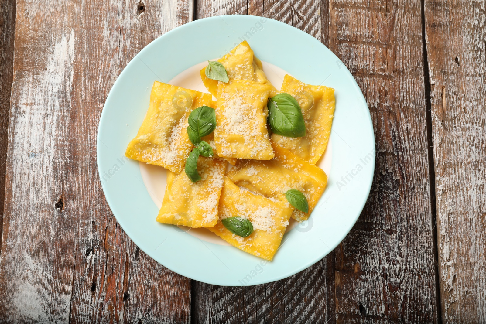 Delicious ravioli with cheese and basil on wooden table, top view Photo of Delicious ravioli with cheese and basil on wooden table, top view