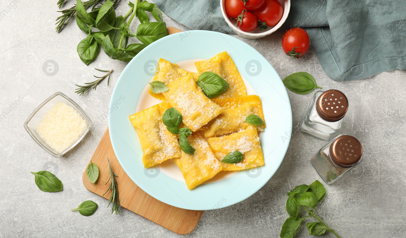 Delicious ravioli with cheese and basil served on grey table, flat lay Photo of Delicious ravioli with cheese and basil served on grey table, flat lay