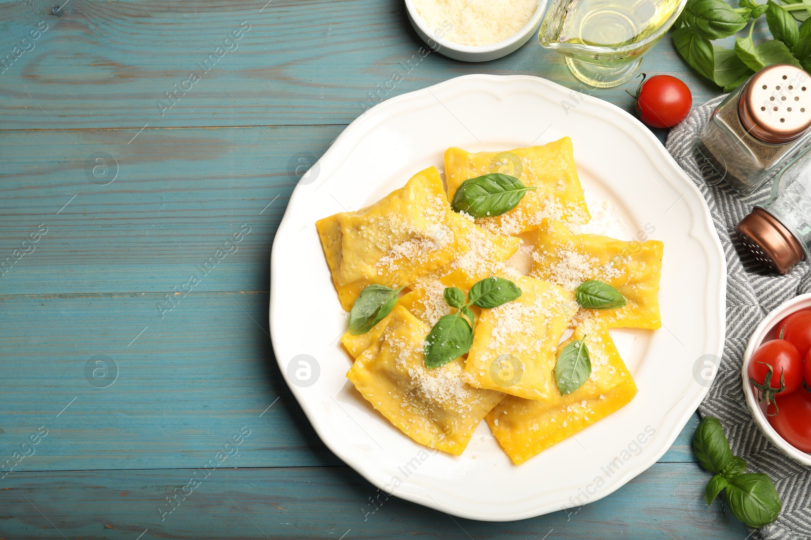 Delicious ravioli with cheese and basil served on light blue wooden table, flat lay. Space for text Photo of Delicious ravioli with cheese and basil served on light blue wooden table, flat lay. Space for text