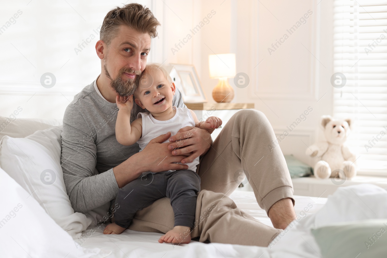 Bedtime. Happy father with his cute little baby on bed at home Photo of Bedtime. Happy father with his cute little baby on bed at home