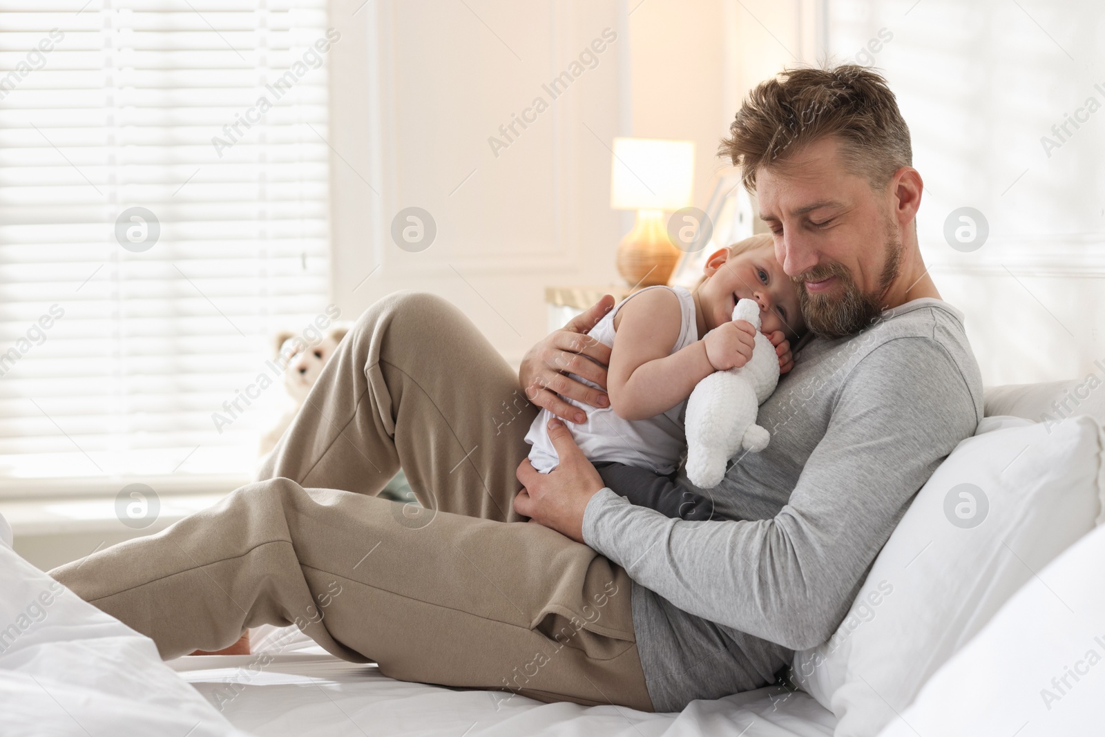 Bedtime. Happy father with his cute little baby on bed at home Photo of Bedtime. Happy father with his cute little baby on bed at home