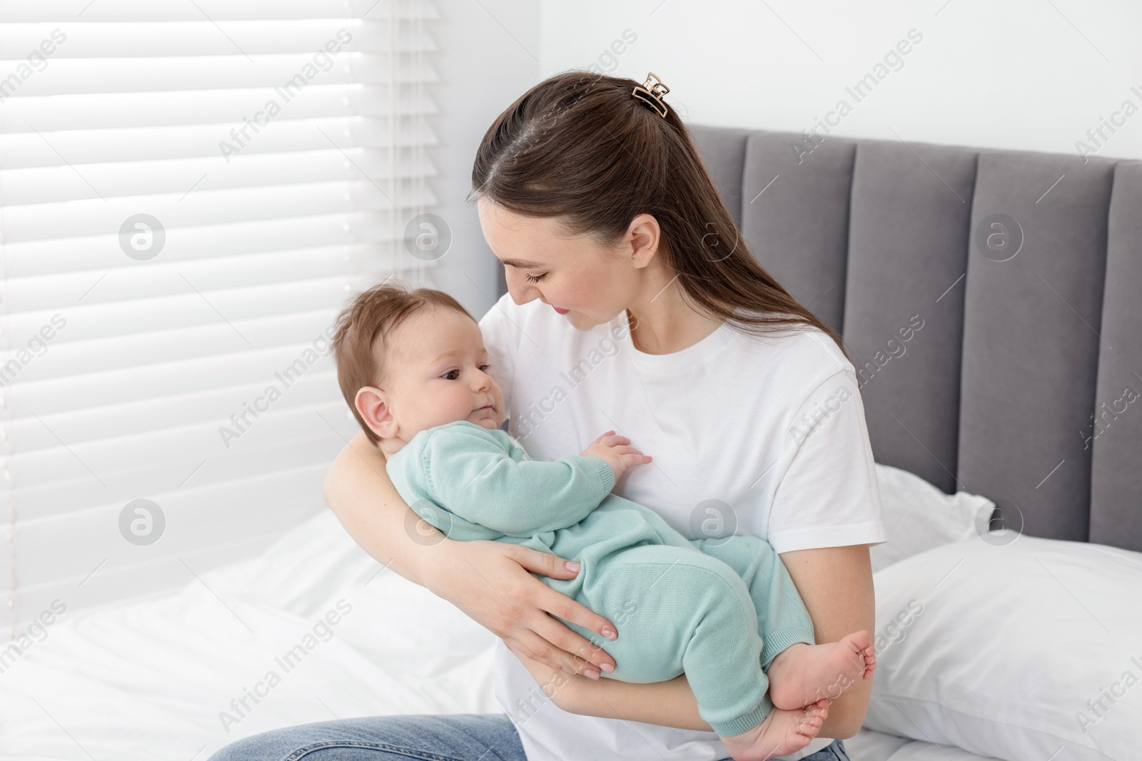Mother with her cute little baby on bed at home Photo of Mother with her cute little baby on bed at home