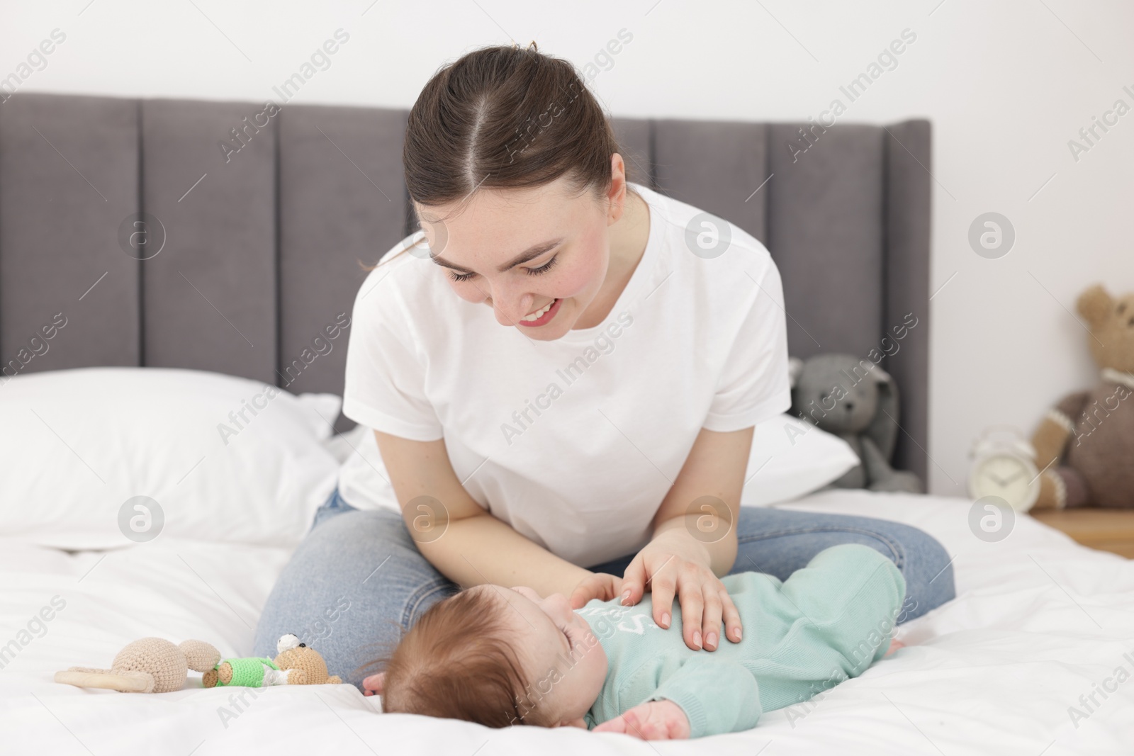 Photo of Mother with her cute little baby on bed at home