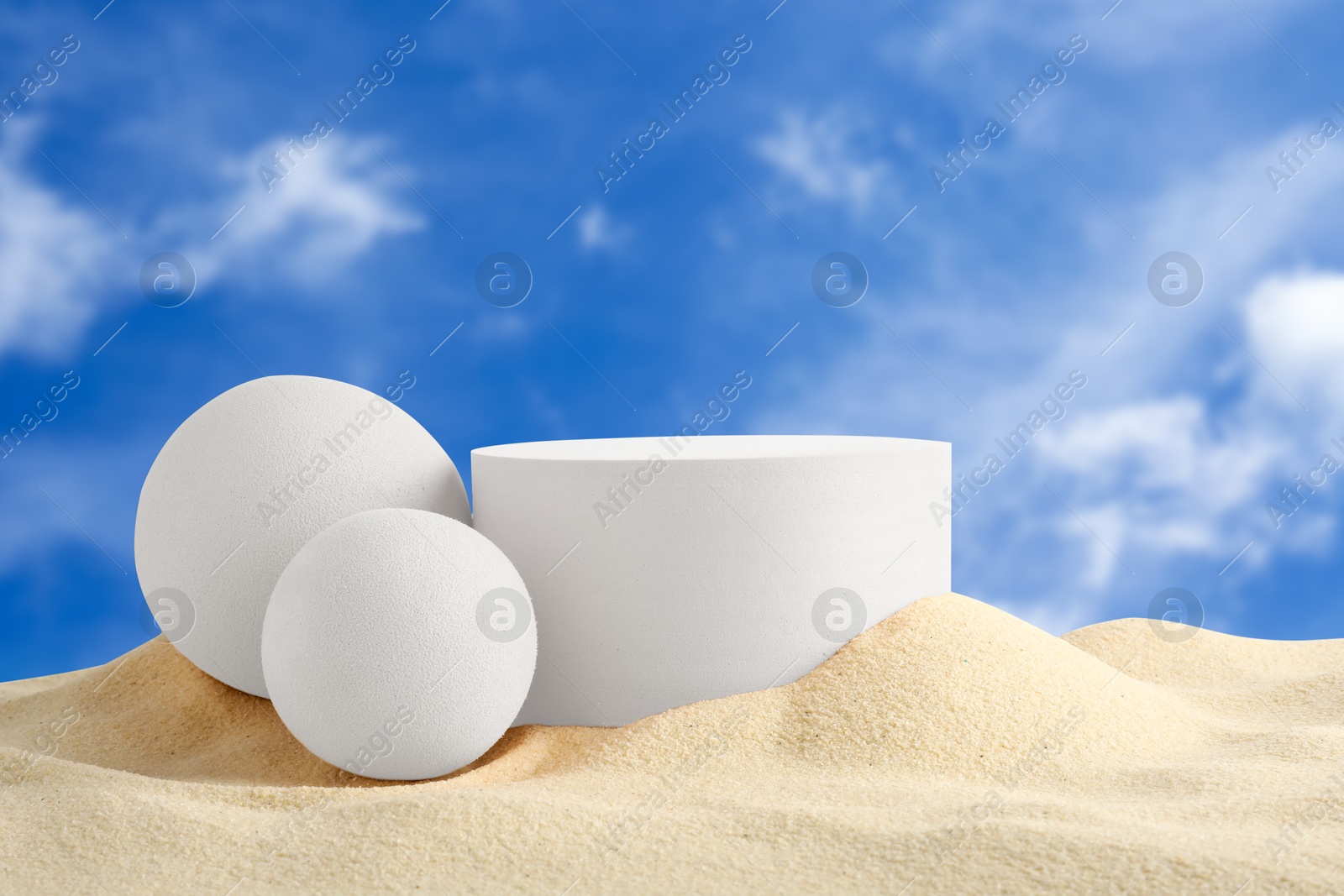 White podium and balls in sand against blue sky Image of White podium and balls in sand against blue sky