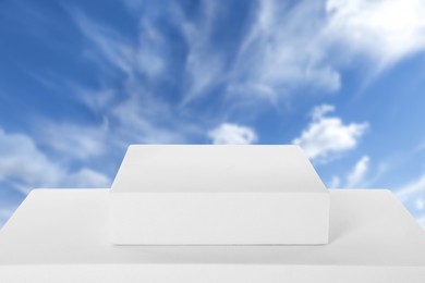 Image of White podium against blue sky with clouds .
