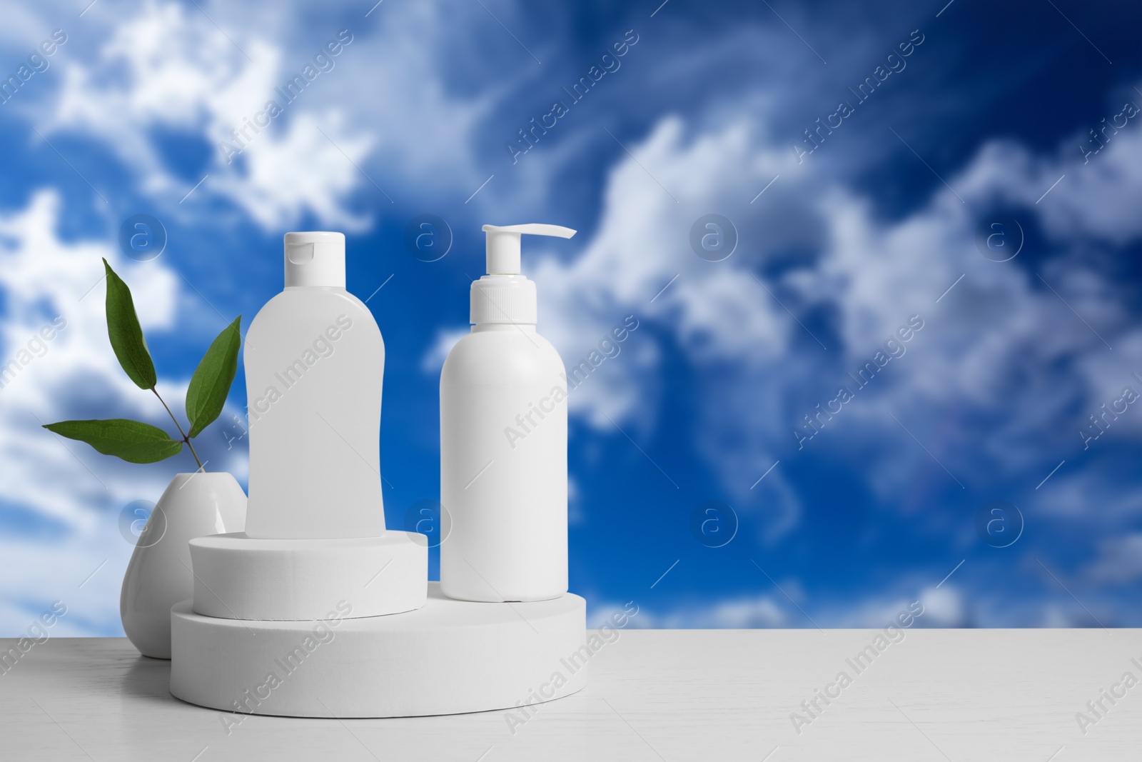 Cosmetic products on white podium against blue sky Image of Cosmetic products on white podium against blue sky