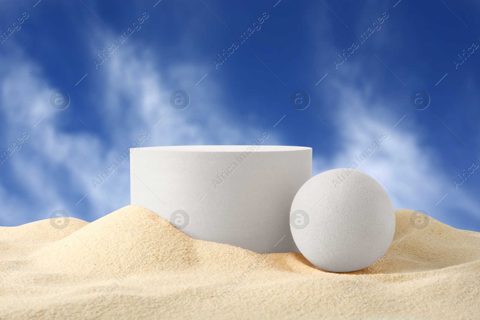 White podium and ball in sand against blue sky Image of White podium and ball in sand against blue sky