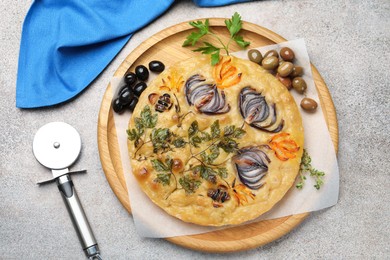 Photo of Delicious focaccia with flowers made of vegetables and cutter on grey table, top view