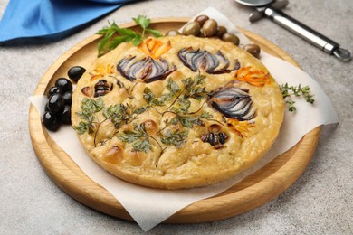 Photo of Delicious focaccia with flowers made of vegetables and cutter on grey table, closeup