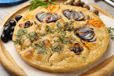 Photo of Delicious focaccia with flowers made of vegetables on table, closeup