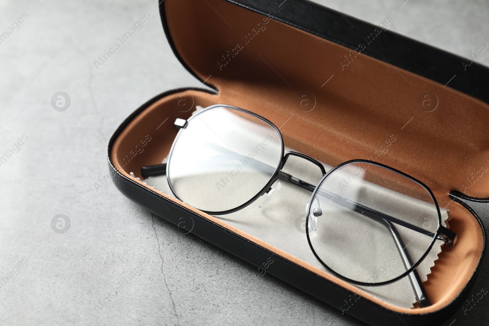 Case with stylish glasses and cleaning cloth on grey table, closeup Photo of Case with stylish glasses and cleaning cloth on grey table, closeup