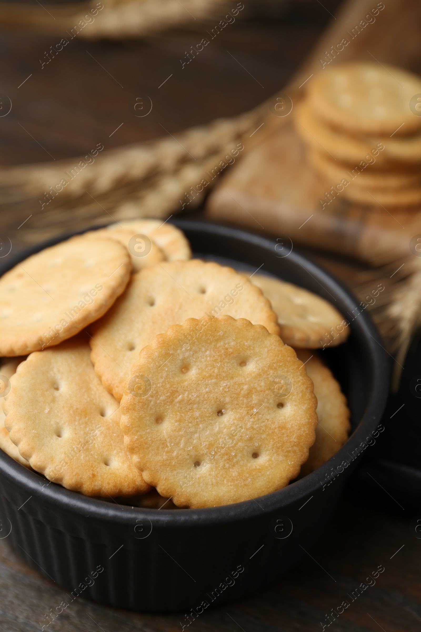 Tasty salty crackers and wheat spikes on wooden table, closeup Photo of Tasty salty crackers and wheat spikes on wooden table, closeup