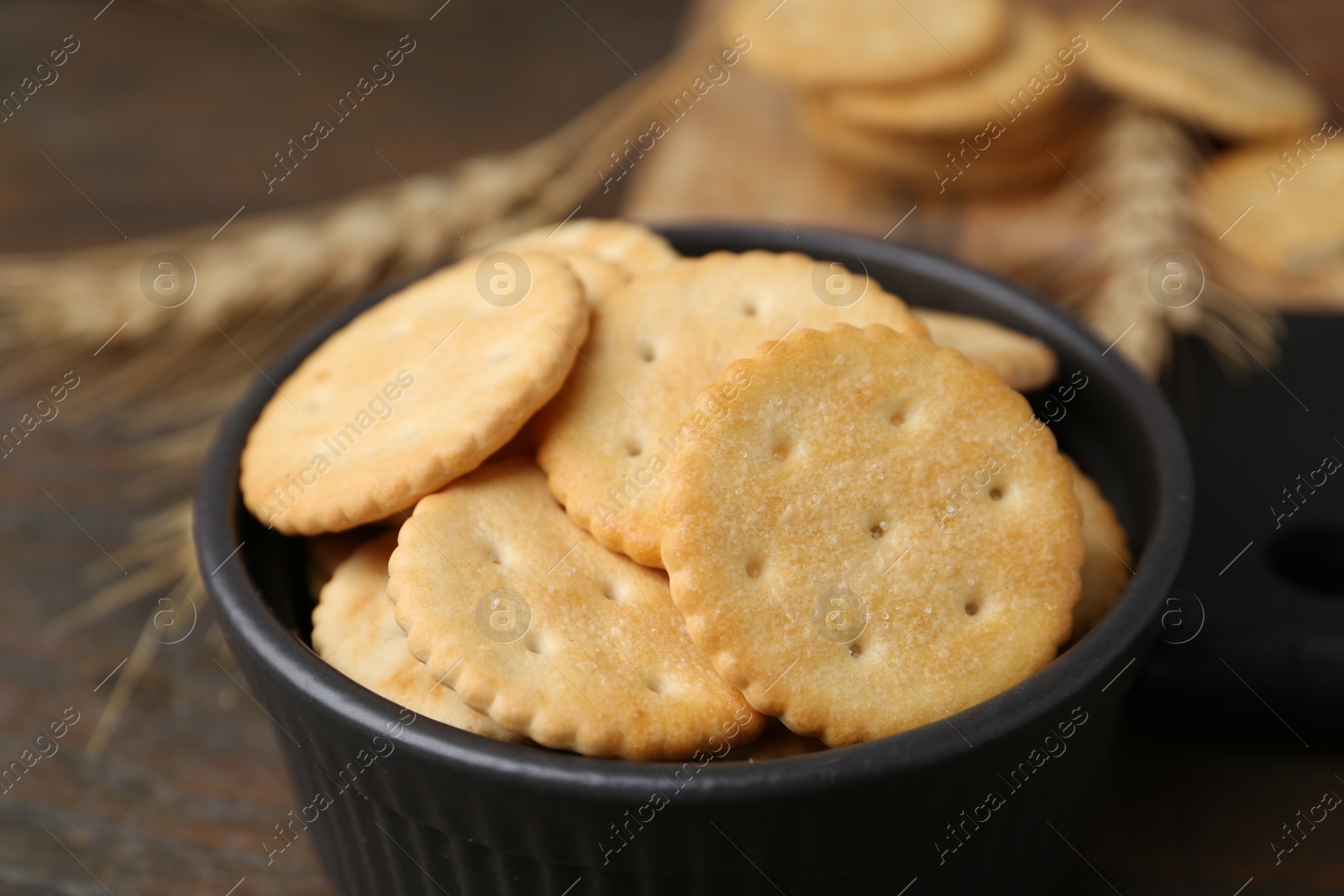 Tasty salty crackers and wheat spikes on wooden table, closeup Photo of Tasty salty crackers and wheat spikes on wooden table, closeup