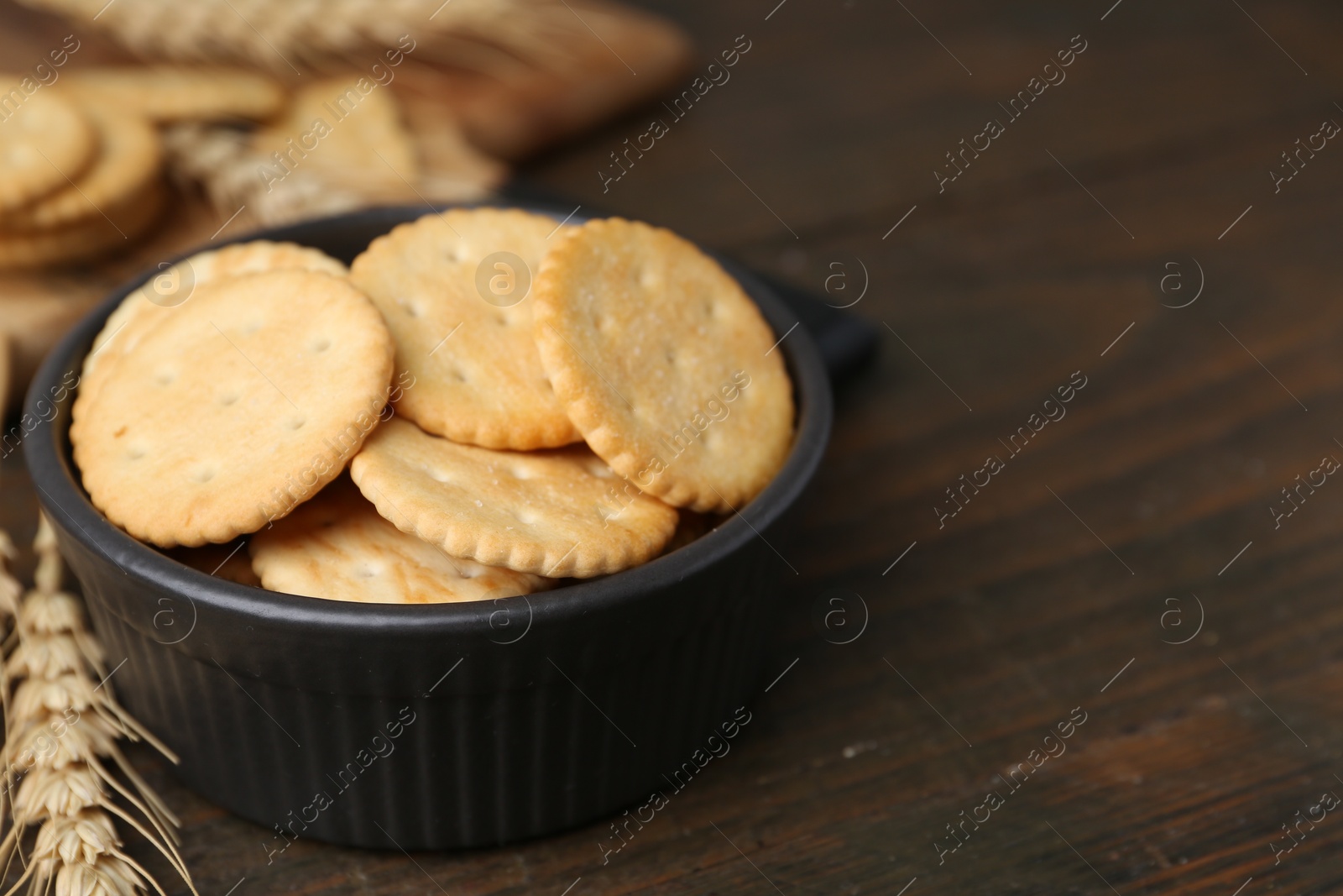 Tasty salty crackers and wheat spikes on wooden table, closeup. Space for text Photo of Tasty salty crackers and wheat spikes on wooden table, closeup. Space for text