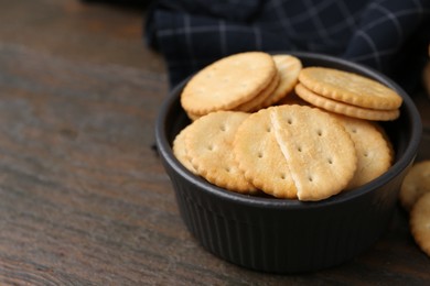 Photo of Tasty salty crackers on wooden table, closeup. Space for text