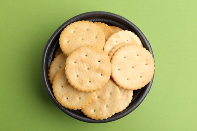 Photo of Tasty salty crackers on green background, top view