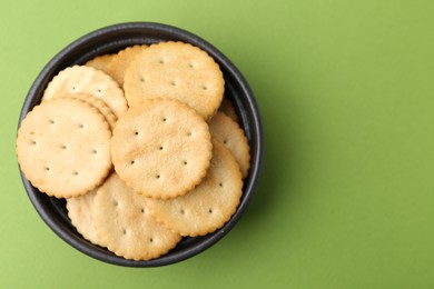 Photo of Tasty salty crackers on green background, top view. Space for text