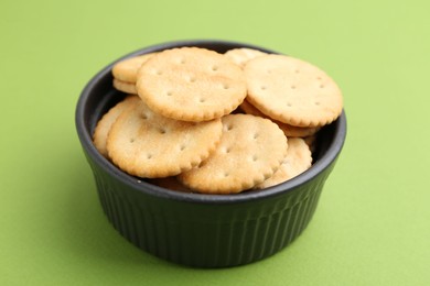 Photo of Tasty salty crackers on green background, closeup