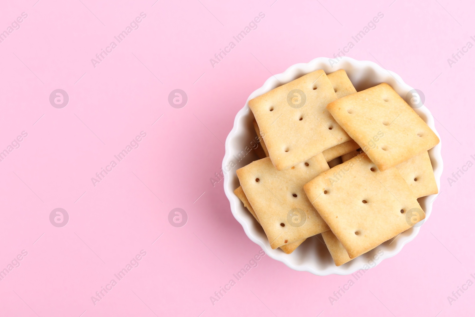 Tasty salty crackers on pink background, top view. Space for text Photo of Tasty salty crackers on pink background, top view. Space for text