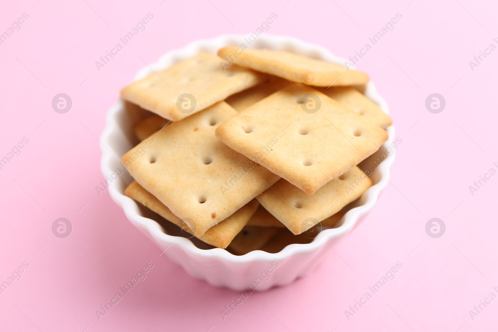 Tasty salty crackers on pink background, closeup Photo of Tasty salty crackers on pink background, closeup