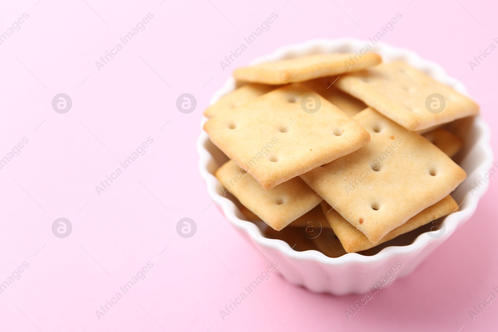 Tasty salty crackers on pink background, closeup. Space for text Photo of Tasty salty crackers on pink background, closeup. Space for text