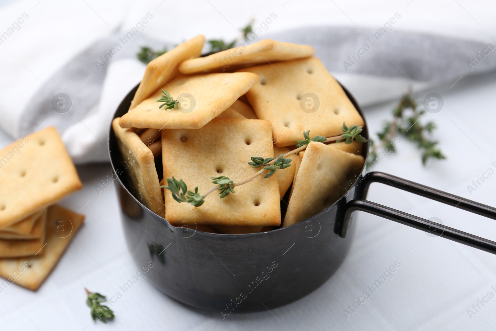 Tasty salty crackers and thyme on white tiled table, closeup Photo of Tasty salty crackers and thyme on white tiled table, closeup