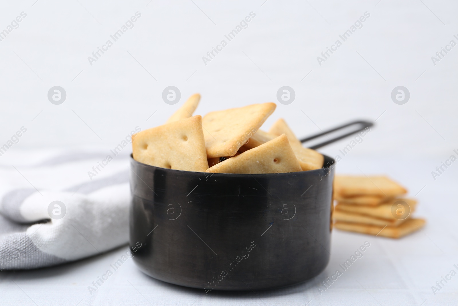 Tasty salty crackers on white tiled table, closeup Photo of Tasty salty crackers on white tiled table, closeup