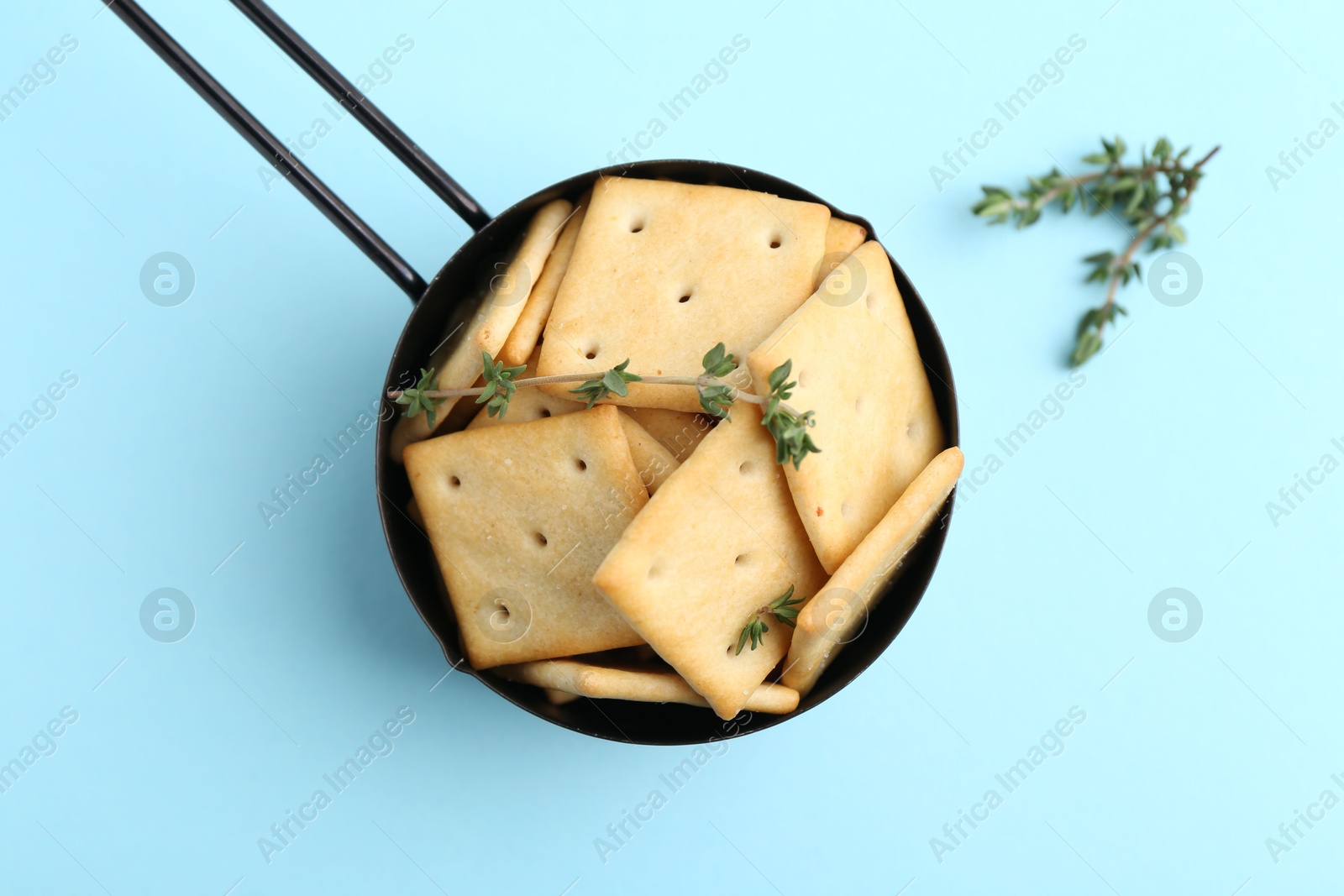 Tasty salty crackers and thyme on light blue background, top view Photo of Tasty salty crackers and thyme on light blue background, top view