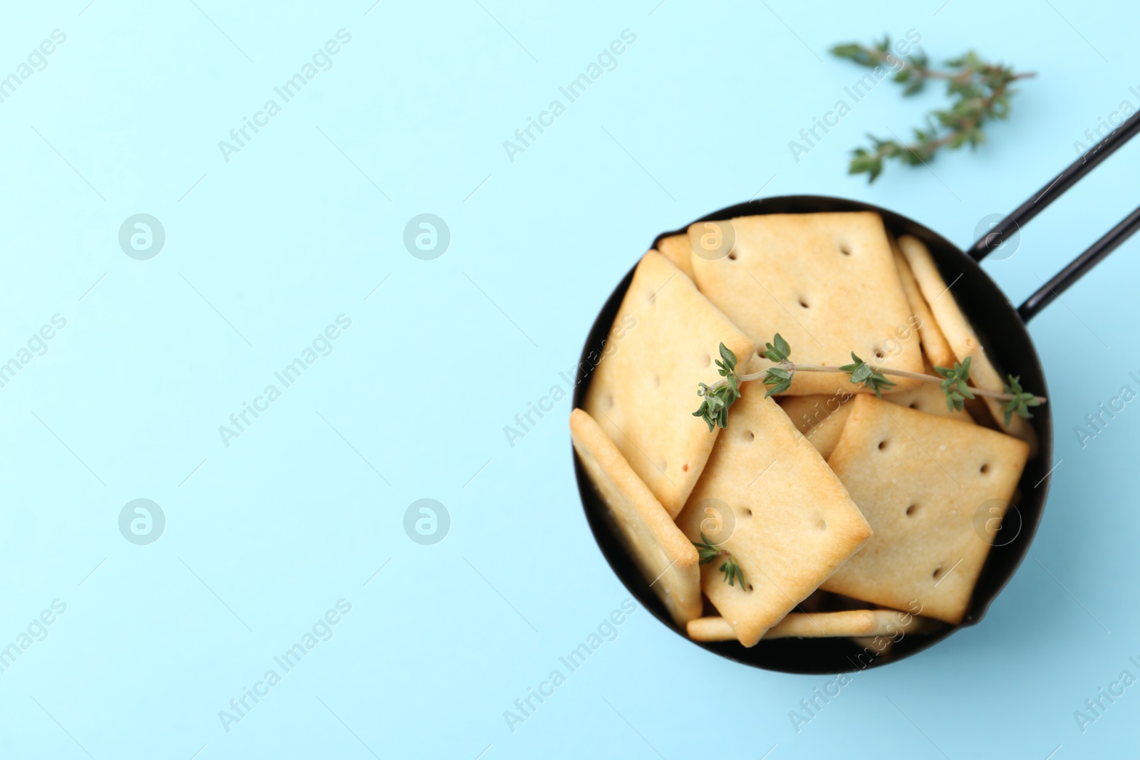 Tasty salty crackers and thyme on light blue background, top view. Space for text Photo of Tasty salty crackers and thyme on light blue background, top view. Space for text