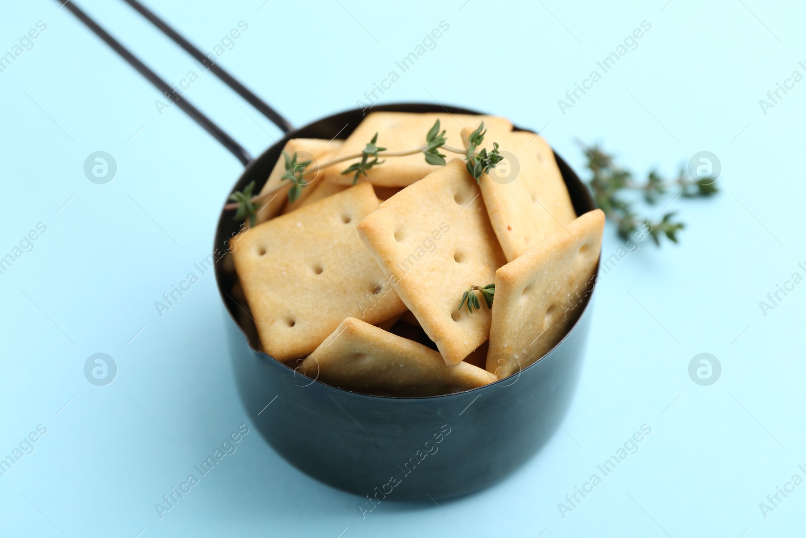 Tasty salty crackers and thyme on light blue background, closeup Photo of Tasty salty crackers and thyme on light blue background, closeup