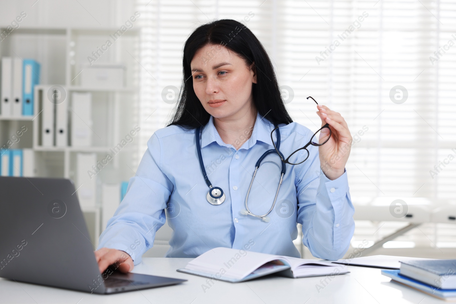 Professional doctor working with laptop at white desk in hospital Photo of Professional doctor working with laptop at white desk in hospital