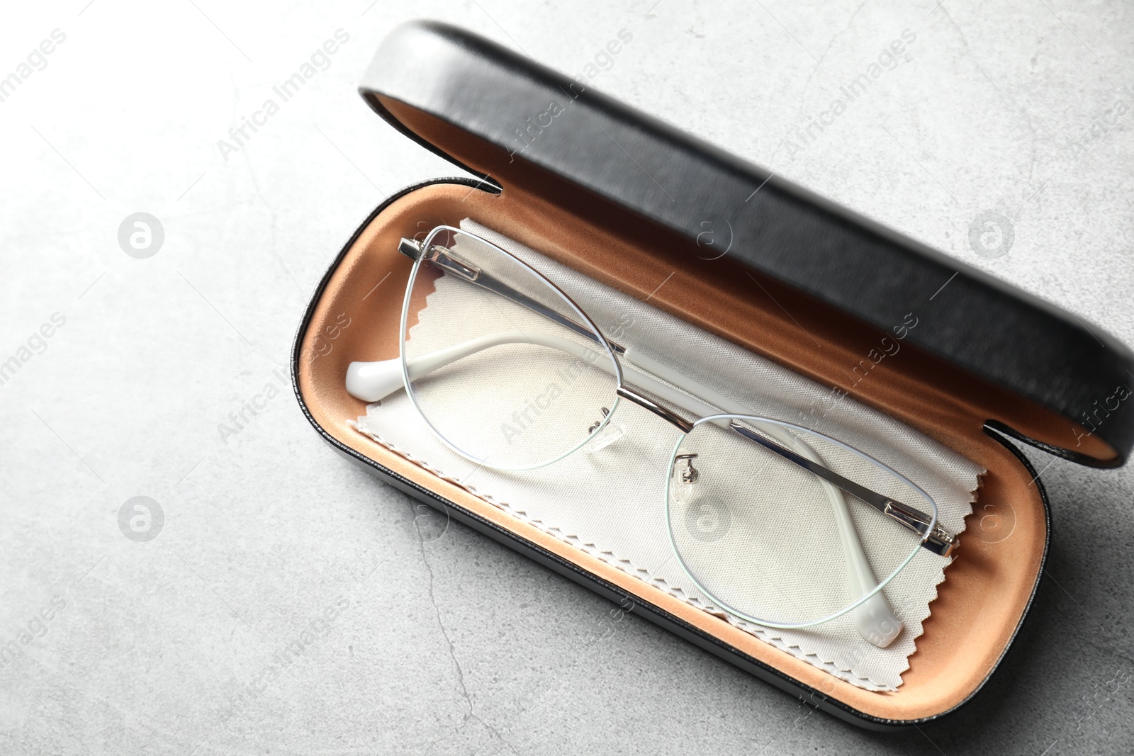 Case with stylish glasses and cleaning cloth on grey table, top view Photo of Case with stylish glasses and cleaning cloth on grey table, top view
