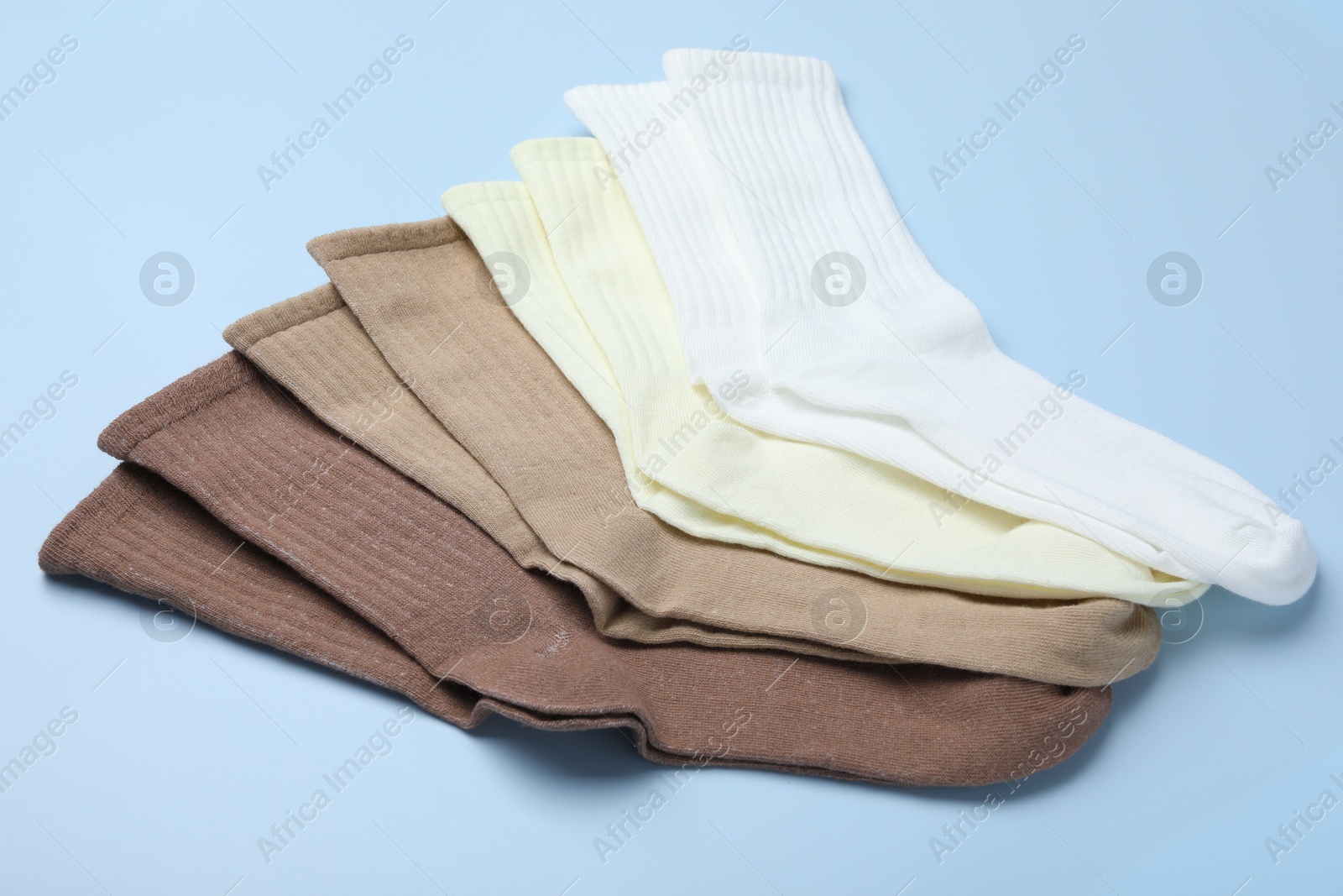 Many different pairs of socks on light blue background, closeup Photo of Many different pairs of socks on light blue background, closeup