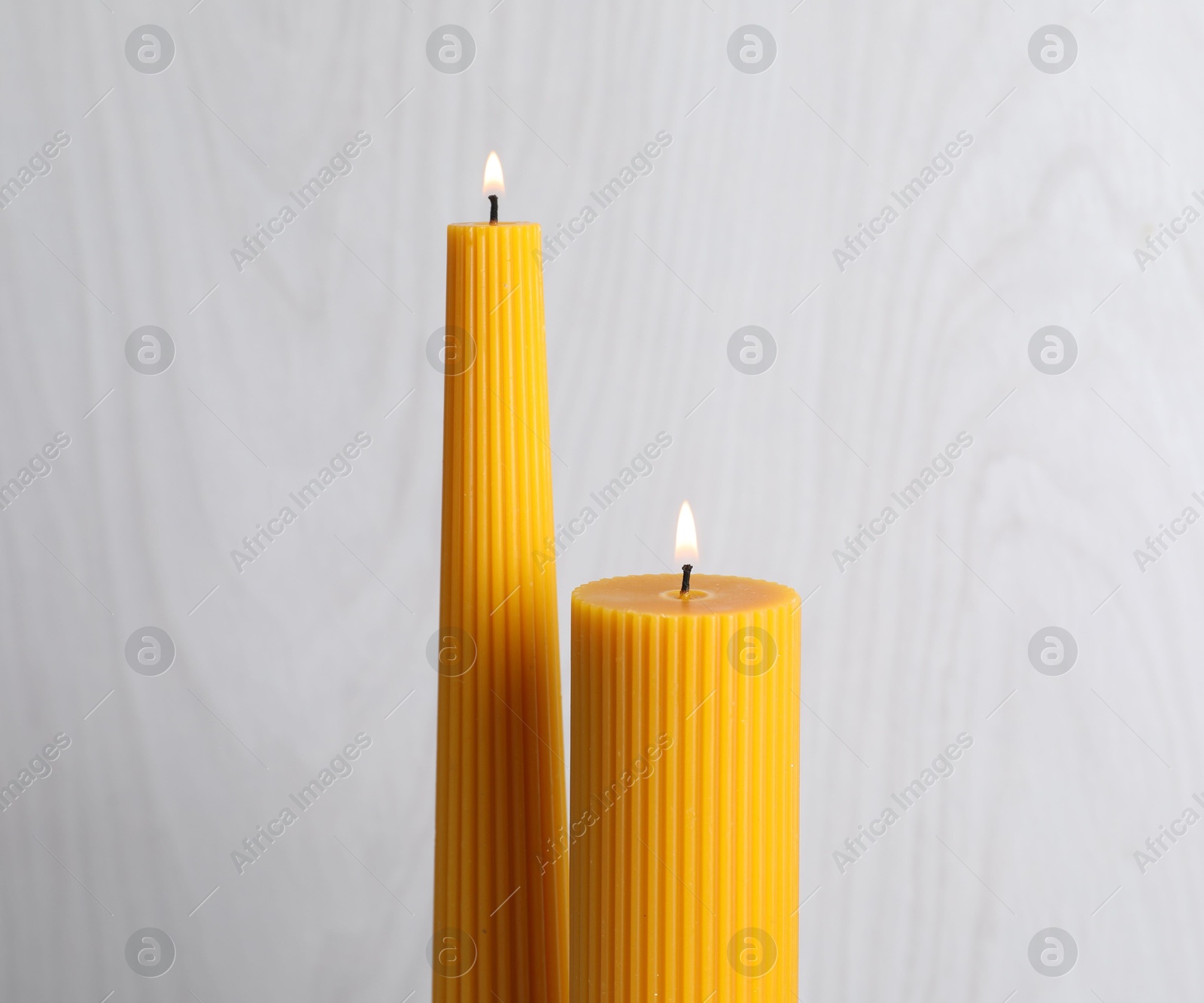Burning beeswax candles on light background, closeup Photo of Burning beeswax candles on light background, closeup