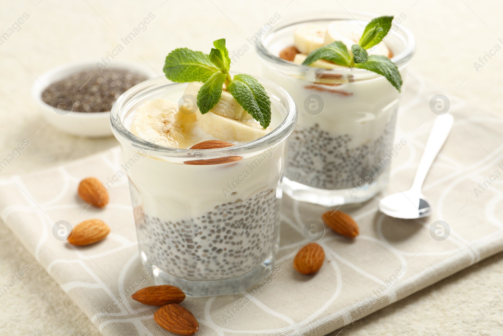 Delicious dessert with chia seeds, yogurt, banana, almond and mint in glasses on light textured table, closeup. Superfood Photo of Delicious dessert with chia seeds, yogurt, banana, almond and mint in glasses on light textured table, closeup. Superfood