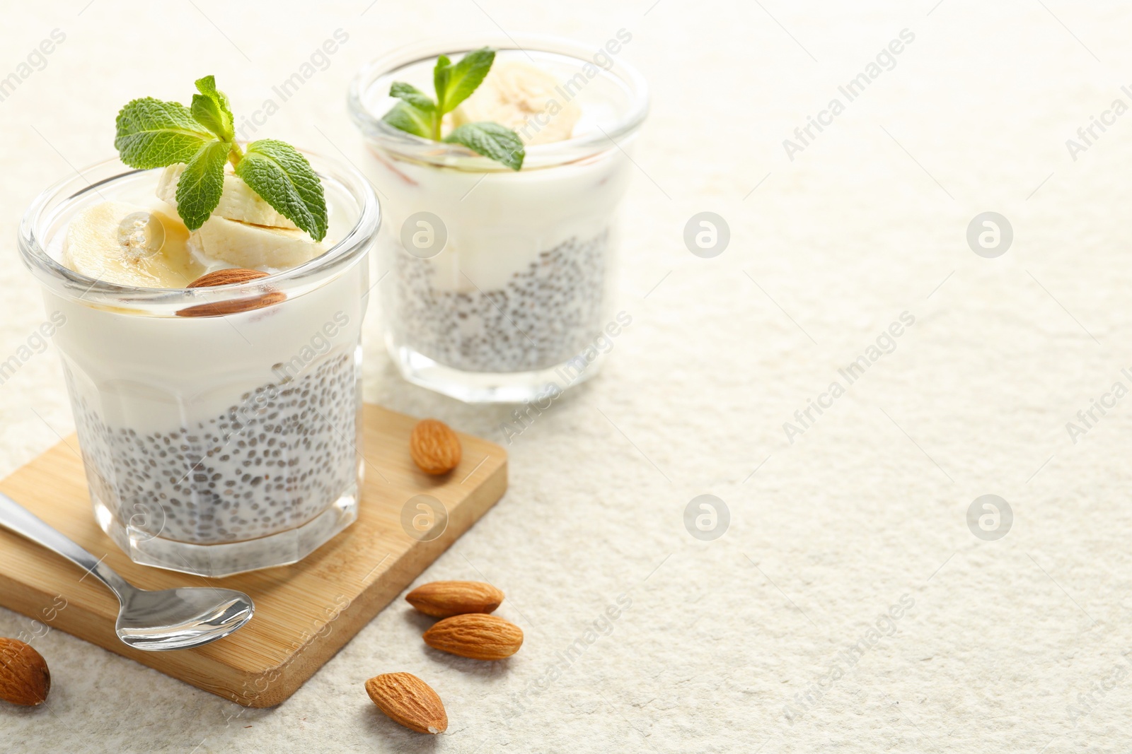 Delicious dessert with chia seeds, yogurt, banana, almond and mint in glasses on light textured table, closeup with space for text. Superfood Photo of Delicious dessert with chia seeds, yogurt, banana, almond and mint in glasses on light textured table, closeup with space for text. Superfood