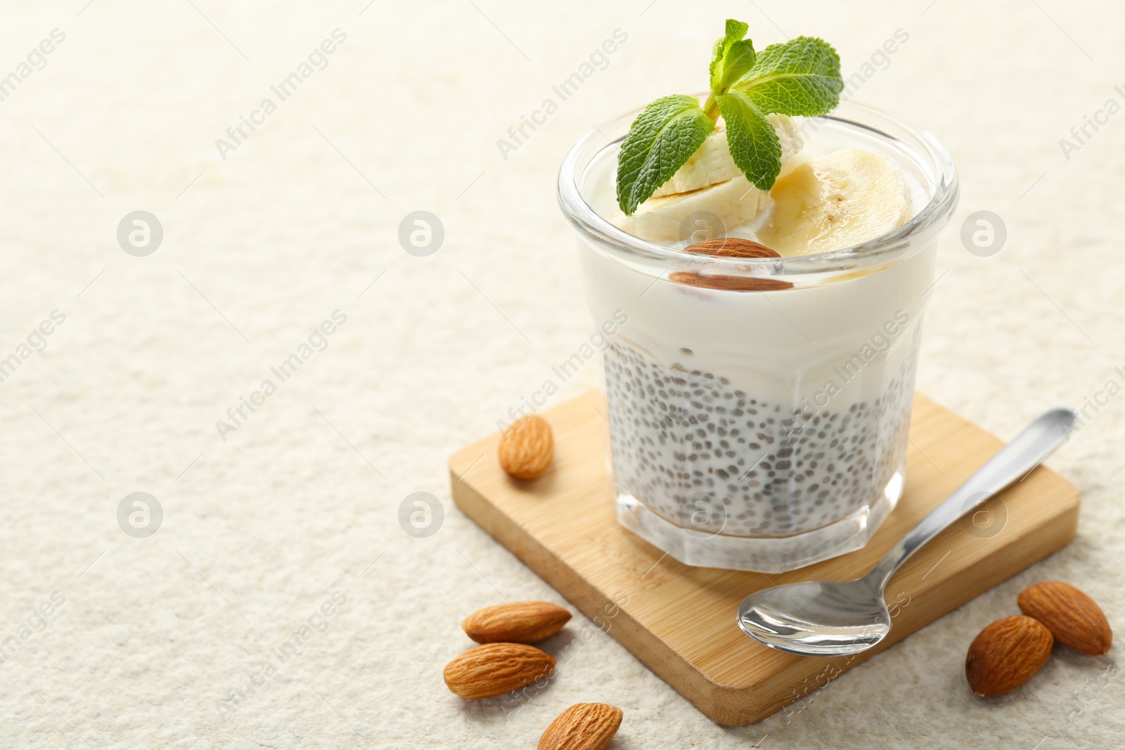 Delicious dessert with chia seeds, yogurt, banana, almond and mint in glass on light textured table, closeup with space for text. Superfood Photo of Delicious dessert with chia seeds, yogurt, banana, almond and mint in glass on light textured table, closeup with space for text. Superfood