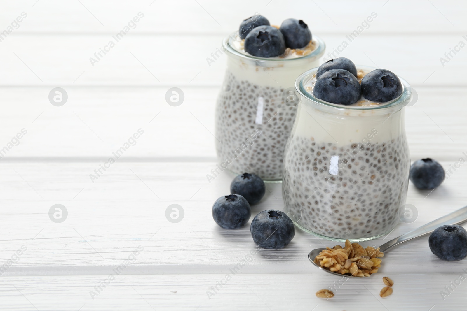 Delicious pudding with chia seeds, yogurt, blueberries and granola on white wooden table, closeup with space for text. Superfood Photo of Delicious pudding with chia seeds, yogurt, blueberries and granola on white wooden table, closeup with space for text. Superfood