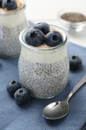 Photo of Delicious pudding with chia seeds, yogurt, blueberries and granola on white table, closeup. Superfood